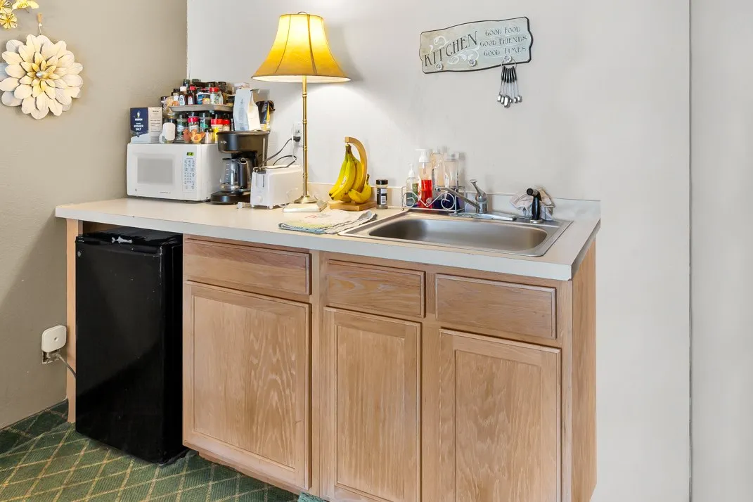 A kitchenette with a sink, wood cabinets, a mini fridge and a microwave